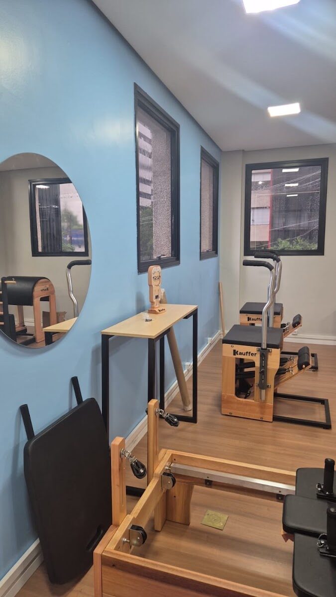 Sala azul com espelho redondo e equipamentos de pilates